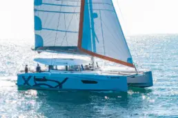 Private catamaran hosting a holiday party on the water at dusk on San Diego Bay with string lights